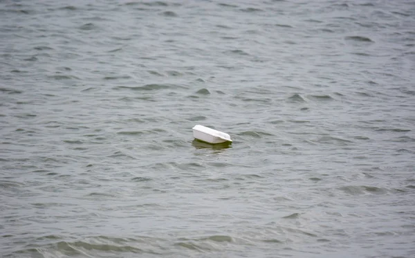 Пластиковая пена плавает по пляжной воде. Экологические проблемы — стоковое фото