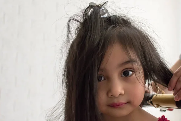 Stylist curling hair for little girl in a parlor