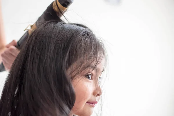 Stylist curling hair for little girl in a parlor
