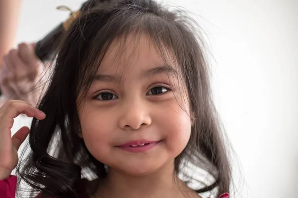 Stylist curling hair for little girl in a parlor