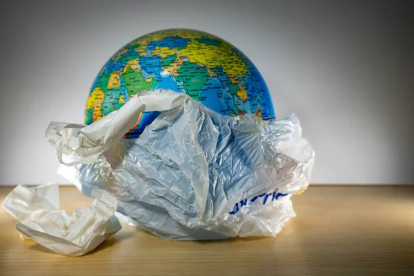 Plastic with earth inside and some trash. Earth is being destroyed because of too much garbage like plastic