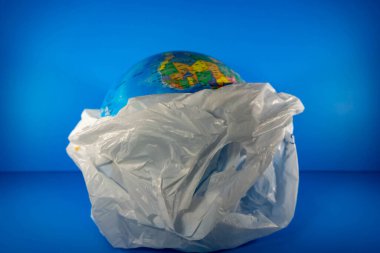 Market Plastiği, içinde toprak ve mavi arka plan var. Dünya, plastik gibi çok fazla çöp yüzünden yok oluyor.