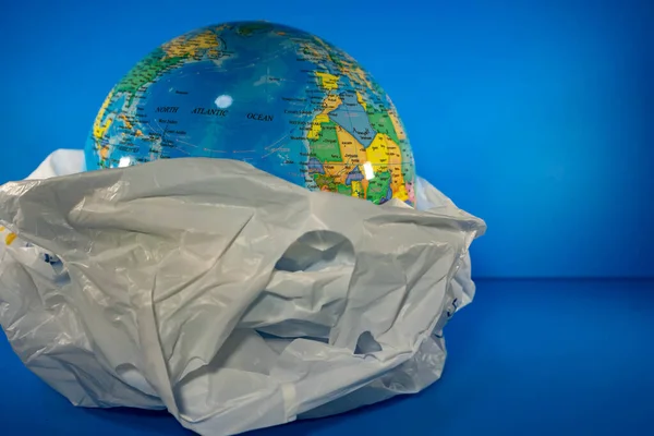 Grocery Plastic with earth inside with blue background. Earth is being destroyed because of too much garbage like plastic