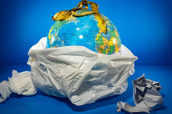 Grocery Plastic with earth inside with blue background. Earth is being destroyed because of too much garbage like plastic