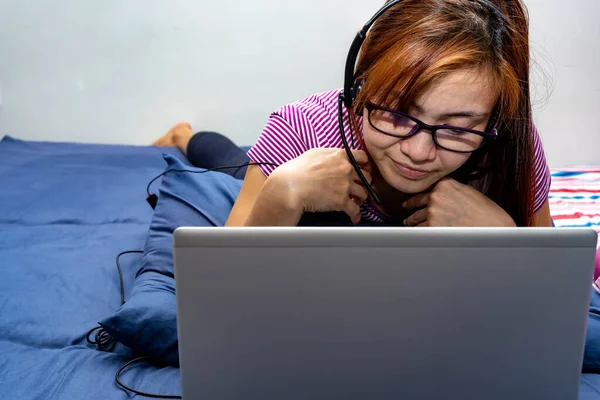 Uma Garota Trabalhando Casa Sua Cama Com Laptop Fone Ouvido — Fotografia de Stock