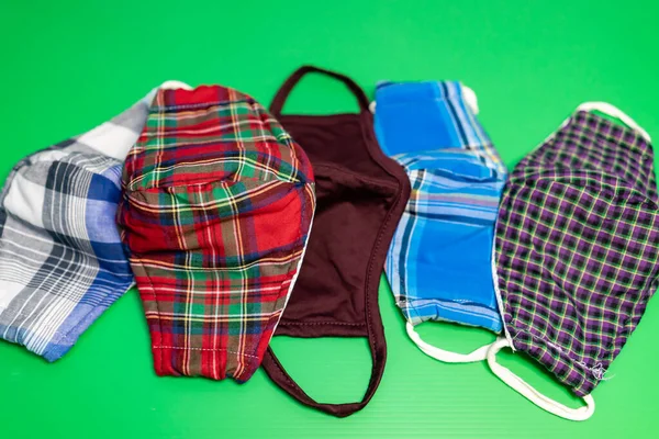 Yeşil arka planda yıkanabilir yüz maskelerinin farklı renkleri. Moda maskeleri yeniden kullanılabilir ve yıkanabilir..