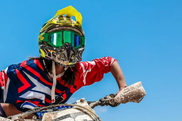 Motokros bisikleti süren bir kadın portresi. Renkli ekipmanı, yarış gözlükleri ve kaskıyla.