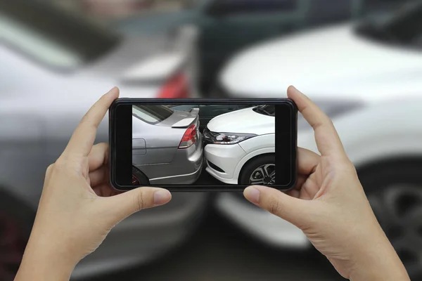 Mão segurando telefone inteligente tirar uma foto na cena de um carro cras — Fotografia de Stock