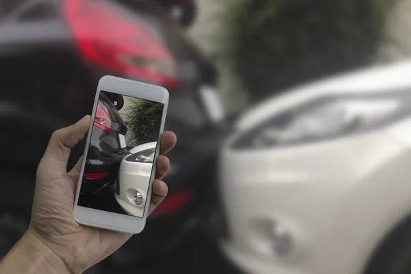 Mão segurando telefone inteligente tirar uma foto na cena de um carro cras — Fotografia de Stock