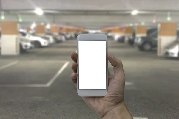Mão segurando smartphone com tela branca em branco sobre Par desfocado — Fotografia de Stock