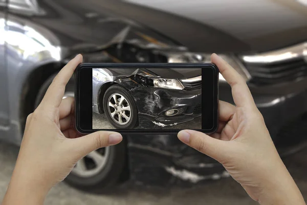 Mão segurando telefone inteligente tirar uma foto na cena de um carro cras — Fotografia de Stock