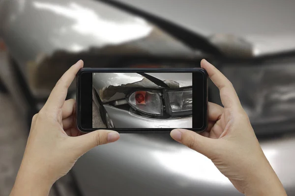 Mão segurando telefone inteligente tirar uma foto na cena de um carro cras — Fotografia de Stock