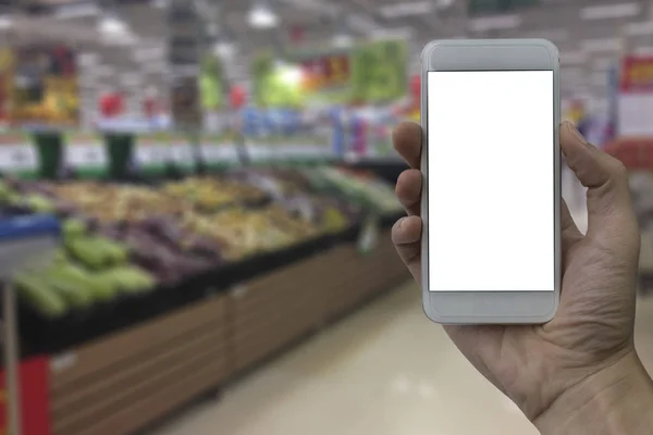 Mão segurando smartphone com tela branca em branco sobre sup desfocado — Fotografia de Stock