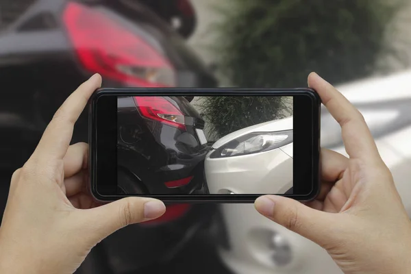 Mão segurando telefone inteligente tirar uma foto na cena de um carro cras — Fotografia de Stock