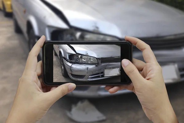 Mão segurando telefone inteligente tirar uma foto na cena de um carro cras — Fotografia de Stock