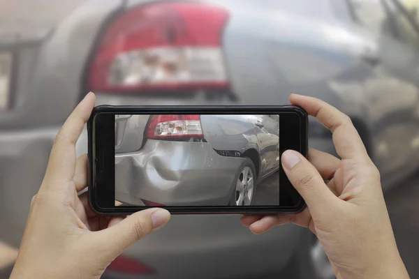 Mão segurando telefone inteligente tirar uma foto na cena de um carro cras — Fotografia de Stock