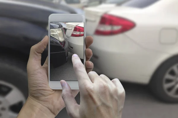 Mão segurando telefone inteligente tirar uma foto na cena de um carro cras — Fotografia de Stock