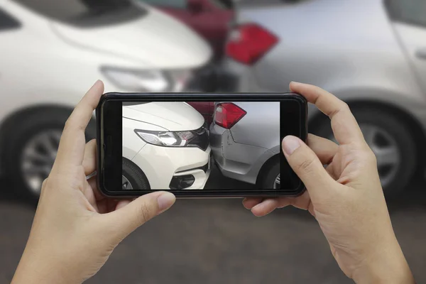 Mână care deține telefonul inteligent face o fotografie la locul unui cras de mașină — Fotografie, imagine de stoc