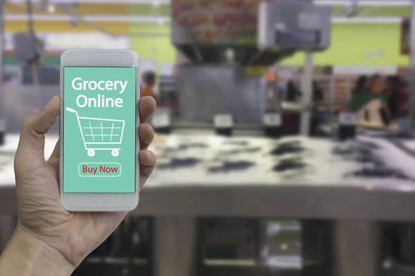 Hand use smartphone with grocery online on screen over blurred s