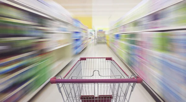 Supermarket aisle with empty shopping cart — Stock Photo, Image