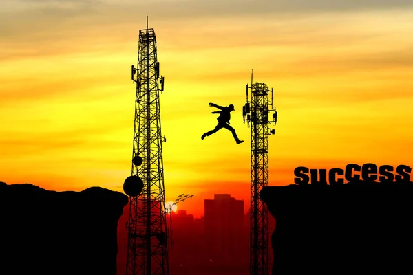 Silhouette of a man jumping over the cliff and Telecommunication — Stock Photo, Image