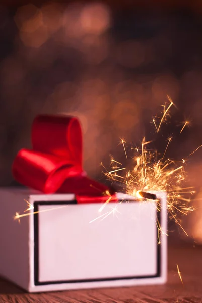 De gift op de tabel, Sparkler, witte doos met een rood lint, — Stockfoto