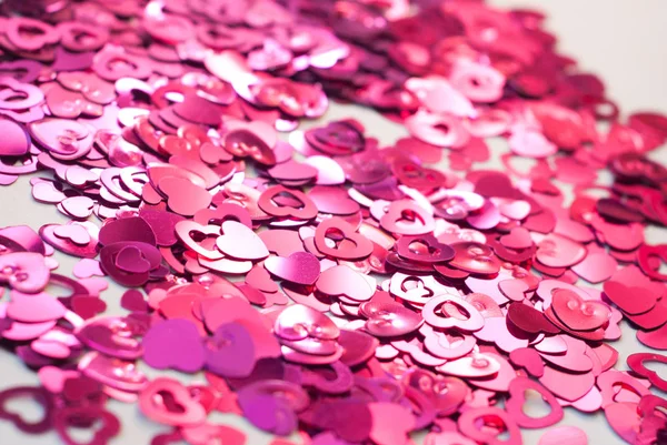 Confetti en forma de corazones esparcidos sobre la mesa . — Foto de Stock