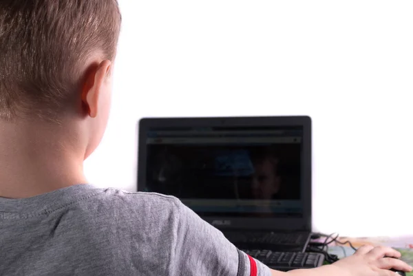 Pequeño niño viendo vídeo en el ordenador portátil sobre un fondo blanco — Foto de Stock