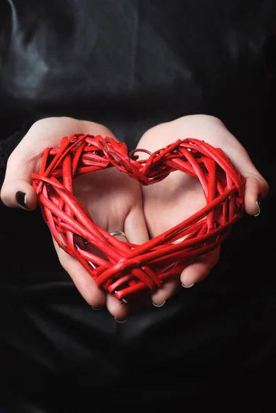 Geweven rood hart in vrouw handen op zwarte achtergrond — Stockfoto