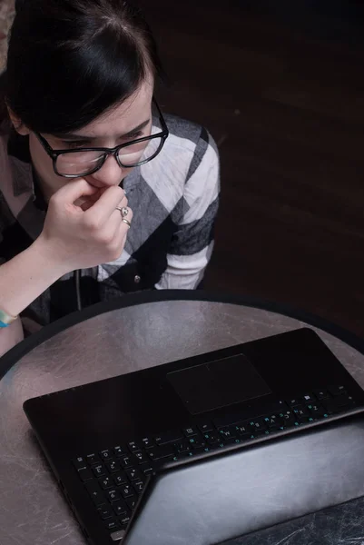 Cute girl working on laptop at home, brunette in black glasses — Stock Photo, Image