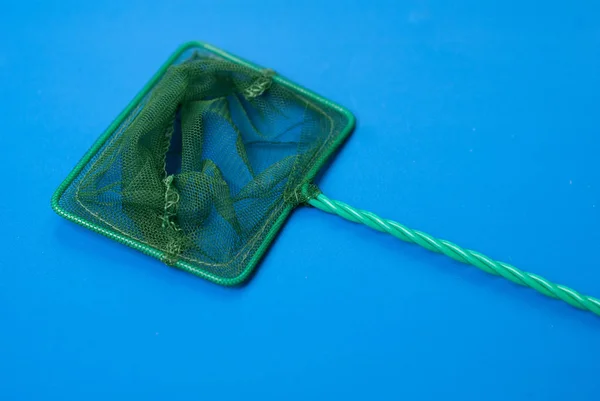 Red verde para la captura de peces del acuario, fondo azul, malla con una célula pequeña — Foto de Stock