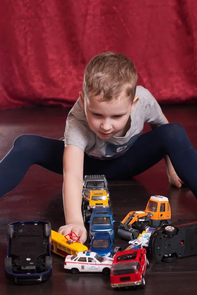 多くのおもちゃの車、床で遊ぶ少年, — ストック写真