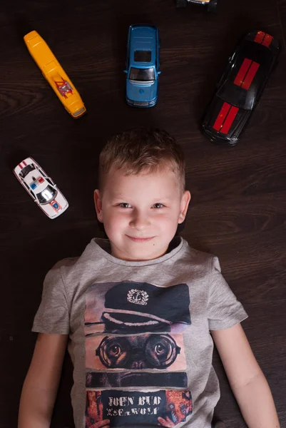 Many toy cars, little boy lying on the floor — Stock Photo, Image