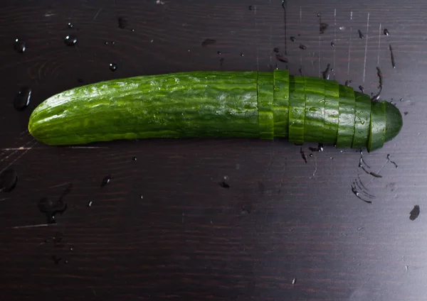 Pepino verde, cortado en rodajas en un tablero negro , — Foto de Stock