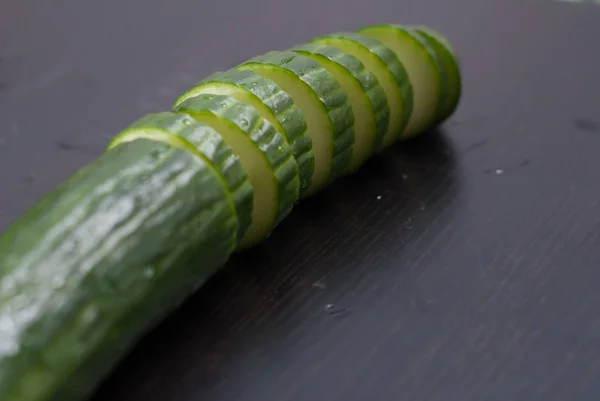 Pepino verde, cortado en rodajas en un tablero negro , — Foto de Stock