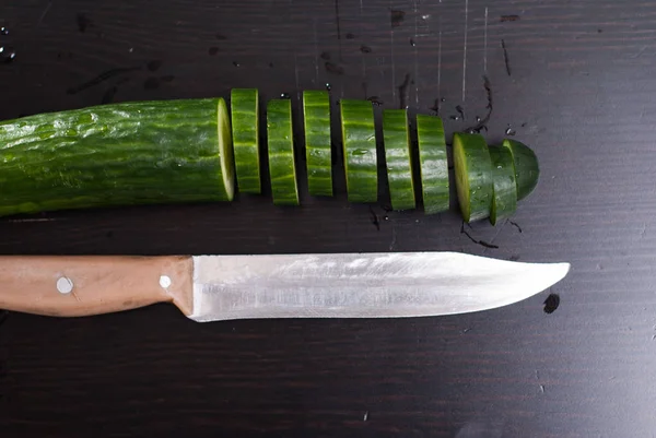 Pepino verde, cortado en rodajas en un tablero negro , — Foto de Stock