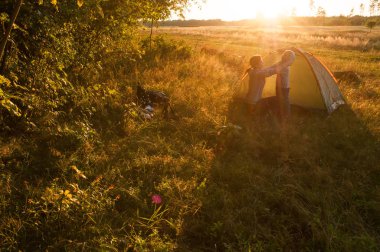 Kamp, anne ve oğul gün batımında çadırda,
