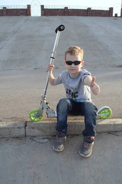 Little boy with sunglasses on a scooter, — Stock Photo, Image