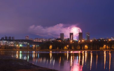 Gölün üzerinde havai fişek, şehrin gece silüeti,