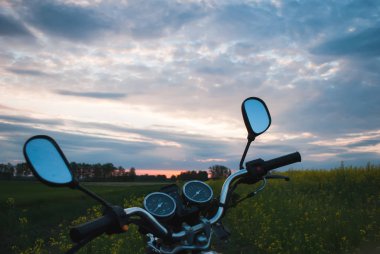 Gün batımı, kolza tohumu sahasında motosiklet,