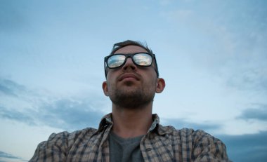 gün batımını izlemek bulutlu gökyüzü arka plan üzerinde güneş gözlüklü genç adam,