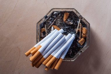 Filtre uygulanmış sigara kirli bir kül tablası ile sigara izmaritleri içinde bir sürü,