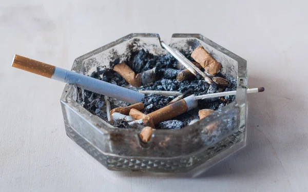 Cigareta s filtrem v špinavý popelník s nedopalky cigaret, konceptuální fotografie, — Stock fotografie
