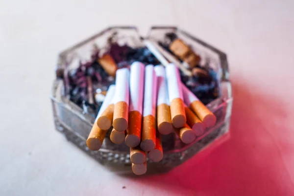 Un tas de cigarettes filtrées dans un cendrier sale avec des mégots de cigarette , — Photo