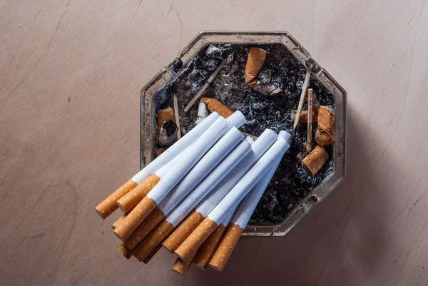 Un tas de cigarettes filtrées dans un cendrier sale avec des mégots de cigarette , — Photo