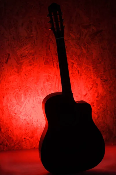 La silhouette è la classica chitarra acustica su fondo rosso — Foto Stock