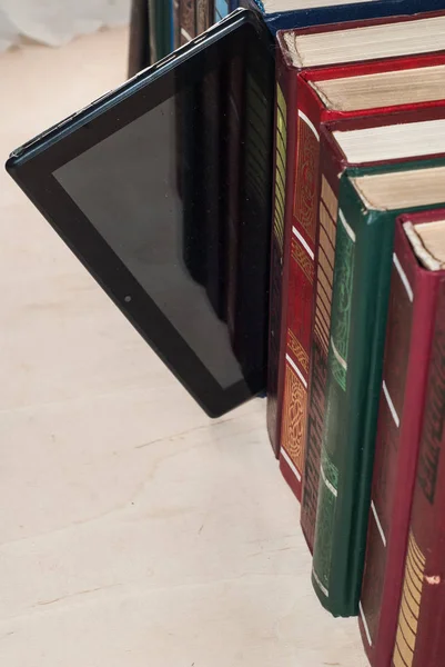 Цифровой планшет на полке с книгами, концепция выбора между старым и новым — стоковое фото