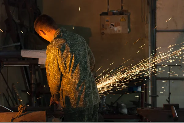 Hombre aserrado de metal con amoladora de disco, el trabajo en la fragua —  Fotos de Stock