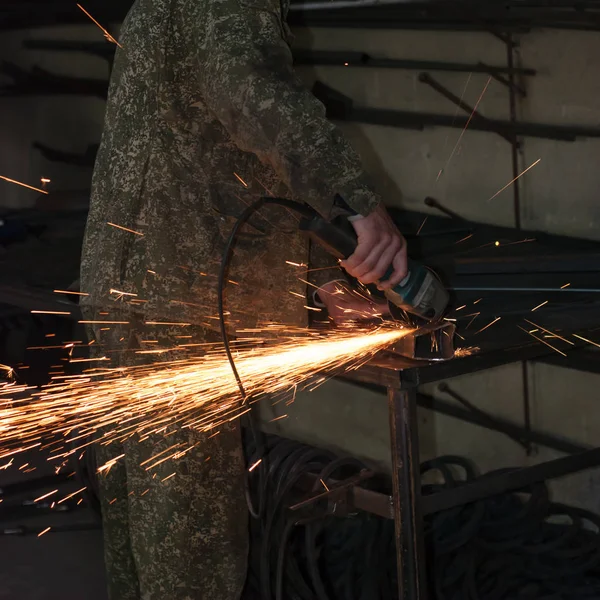 Mann sägt Metall mit Scheibenschleifer, die Arbeit in der Schmiede — Stockfoto