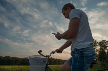 Telefonda gökyüzüne karşı bir bisikletçi bakar,